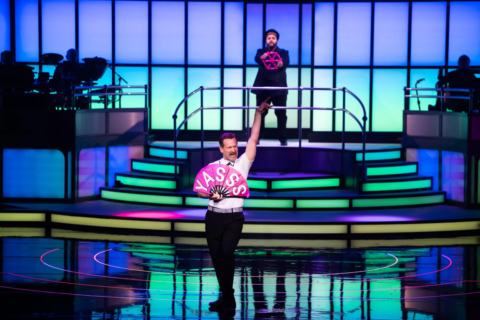 A performer holds up a 'YASSS' sign on the Lido stage, Titaníque Paris